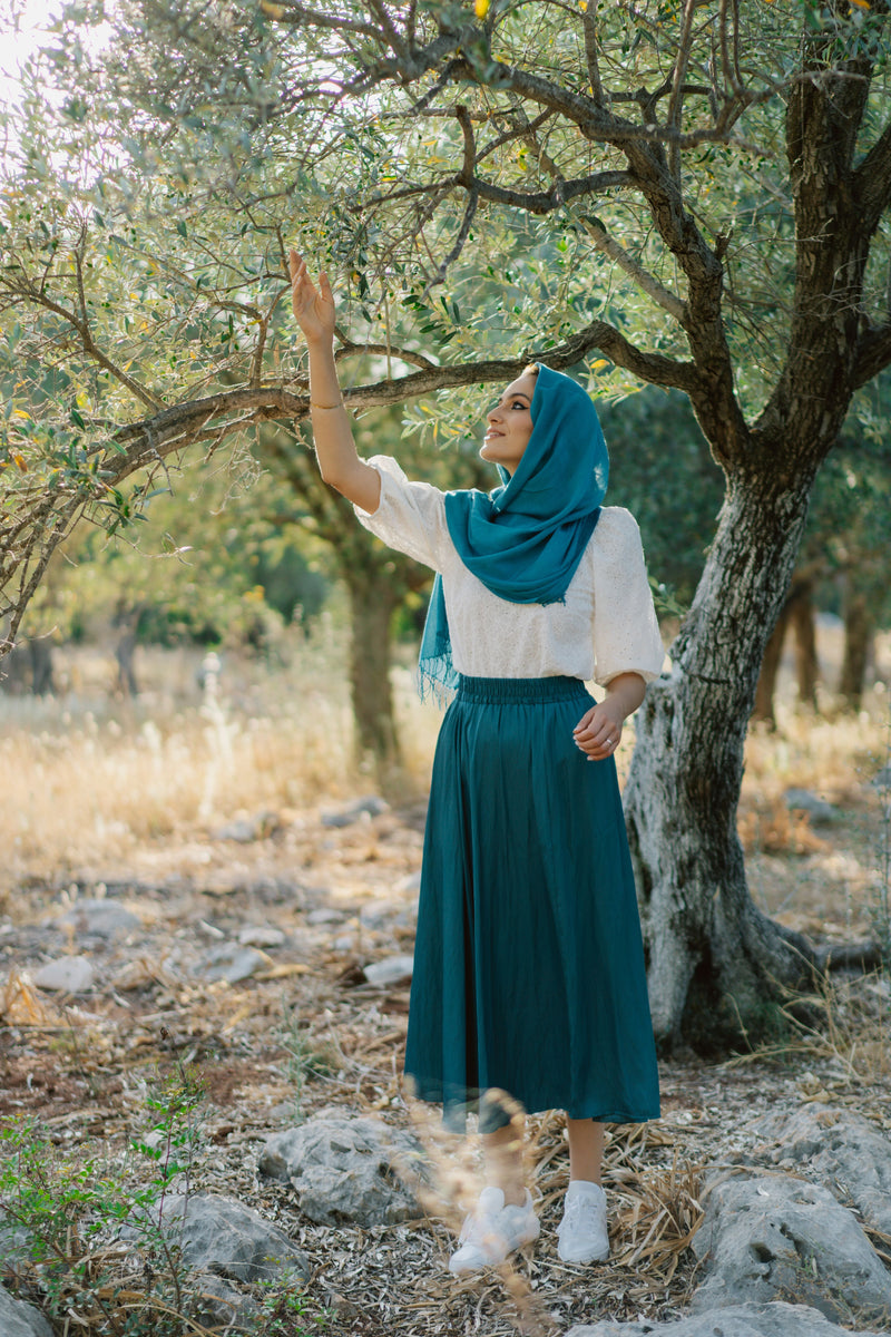 Muslim woman wearing a hijab, white blouse and long blue skirt outdoors, illustrating modest blue skirt and dress styling