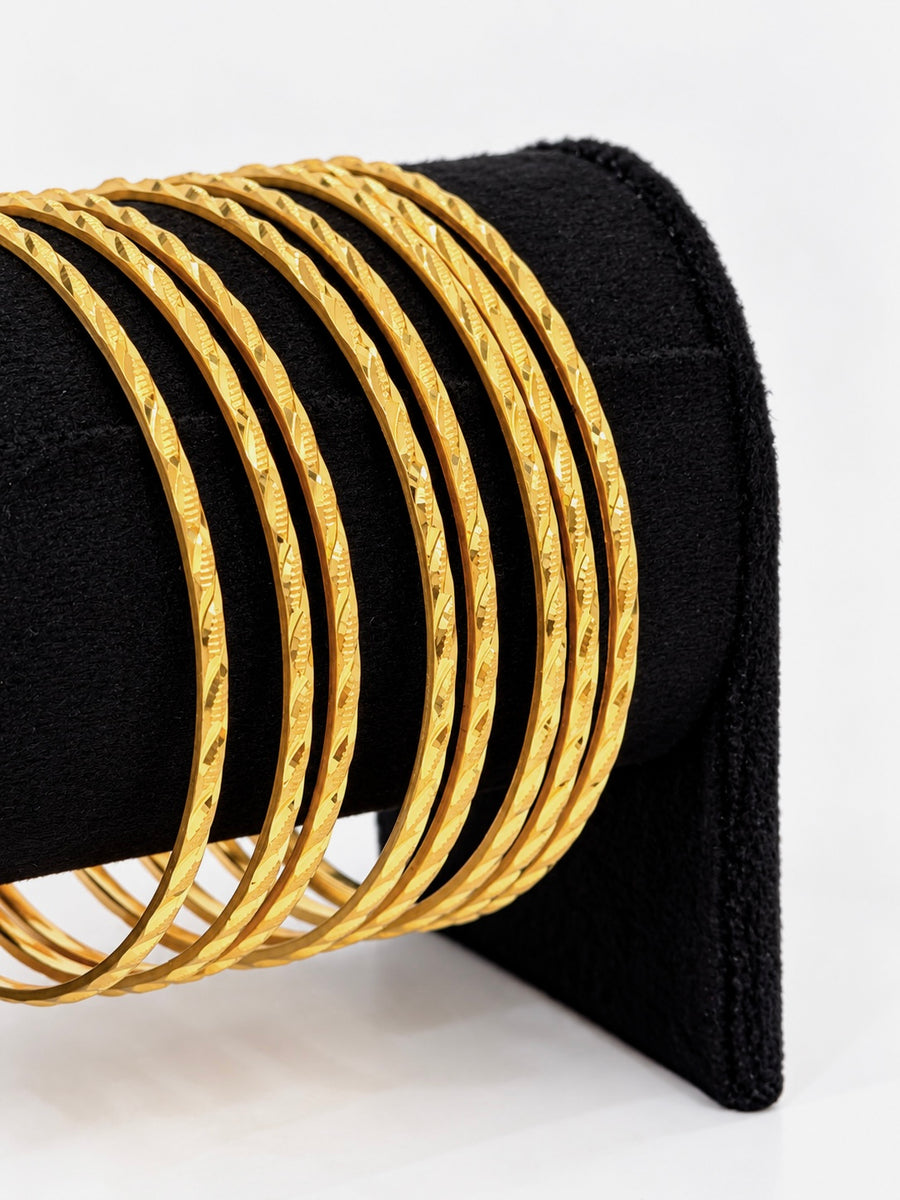 Close-up of 24K gold plated textured bangles on black display stand