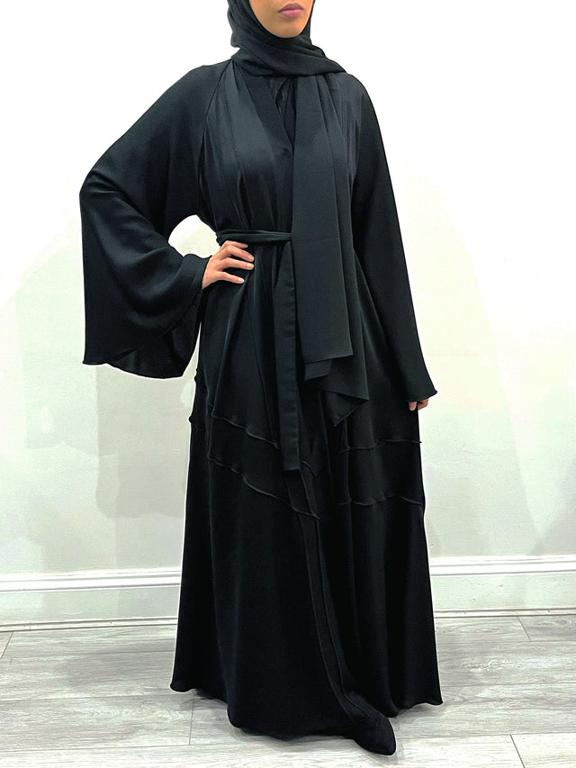Amani's black umbrella-cut open abaya showing the wide flared hem