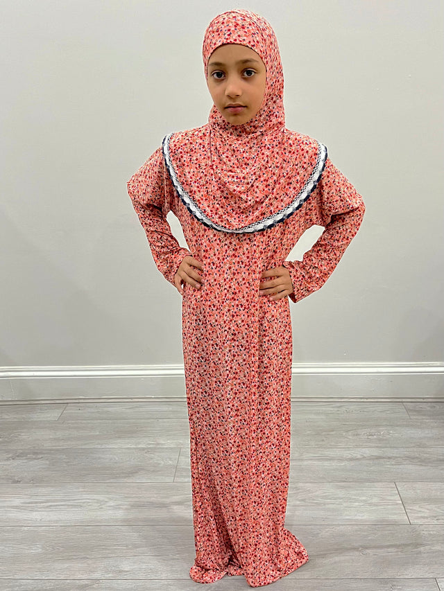 Little girl wearing Amani's coral one-piece slip-on prayer dress with attached hijab