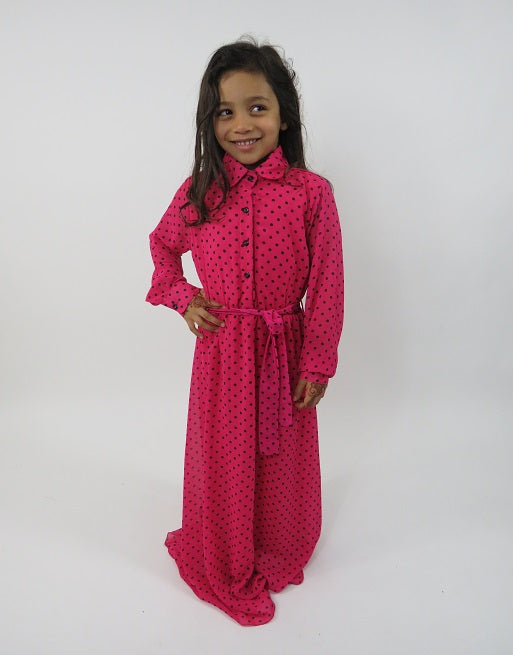 Girl wearing Amani's pink and black polka-dot long-sleeve kids maxi dress