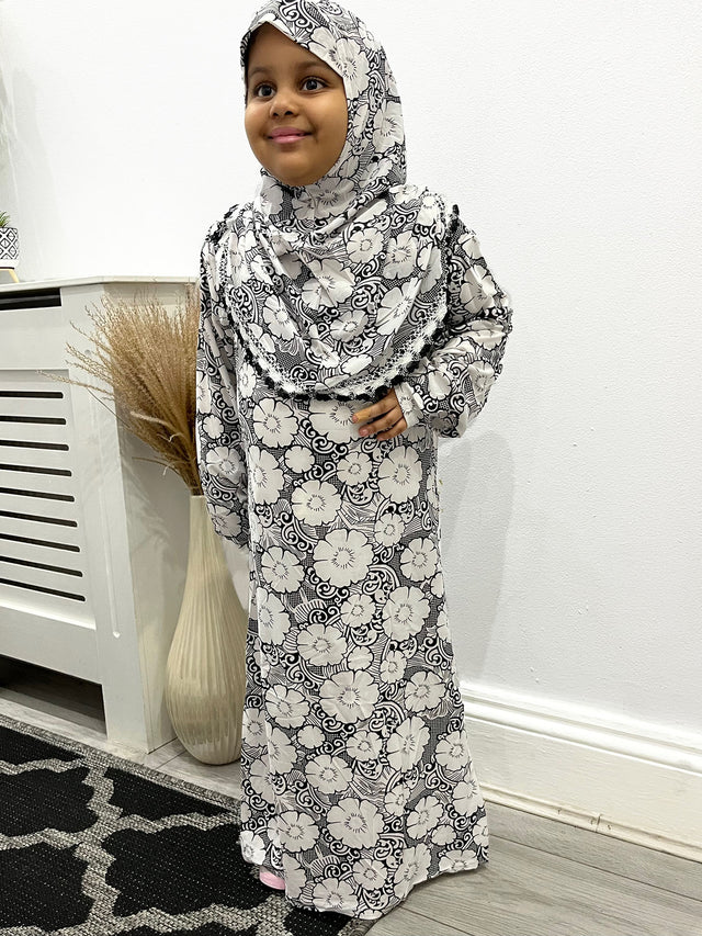 Little girl wearing Amani's black and white floral slip-on prayer dress with attached hijab