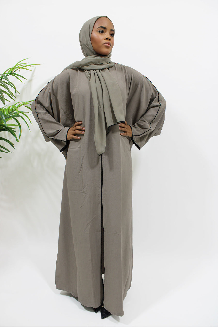 Side view of the taupe open abaya showing the black embellished detailing