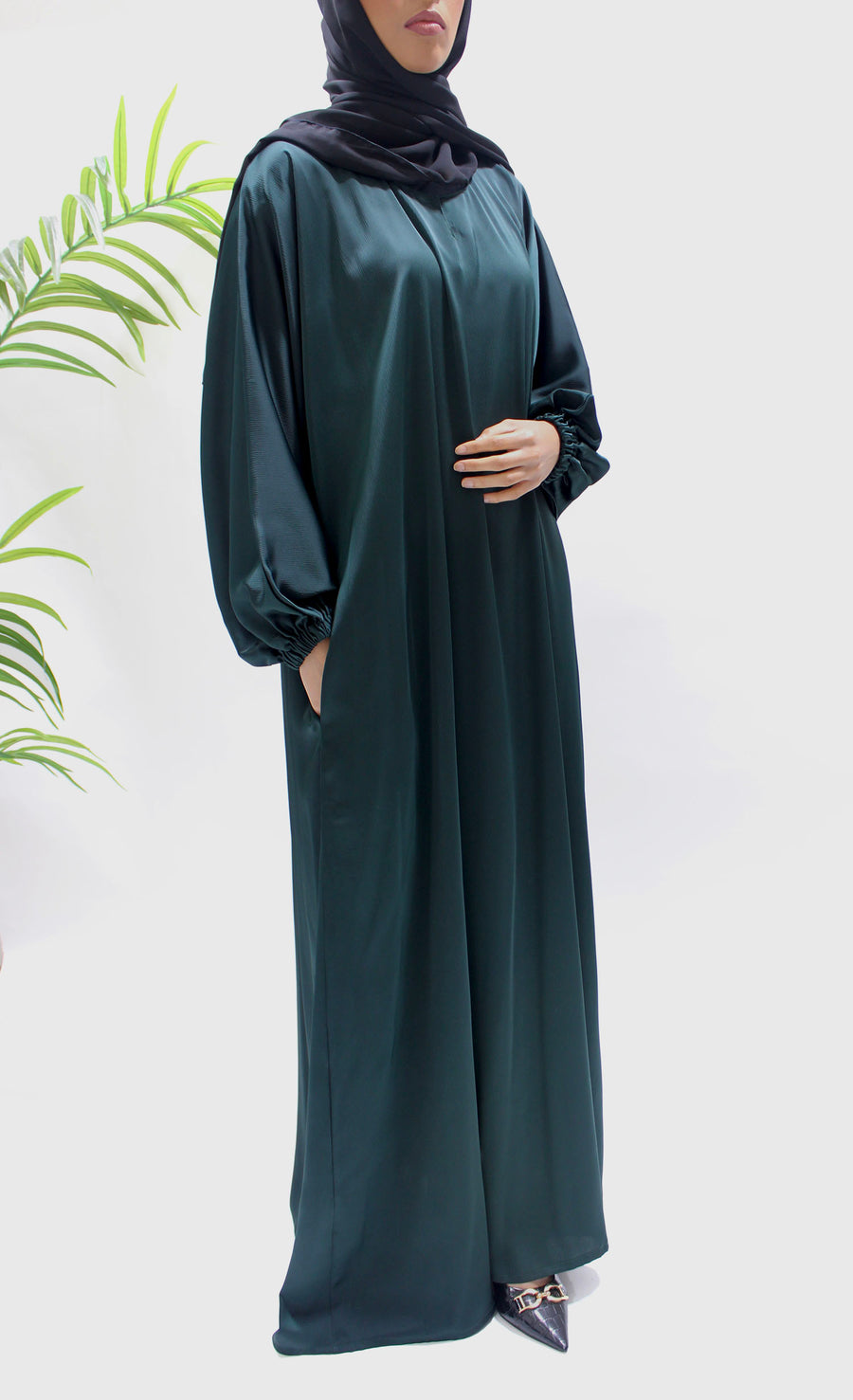 Full-length view of Amani's bottle green textured satin abaya
