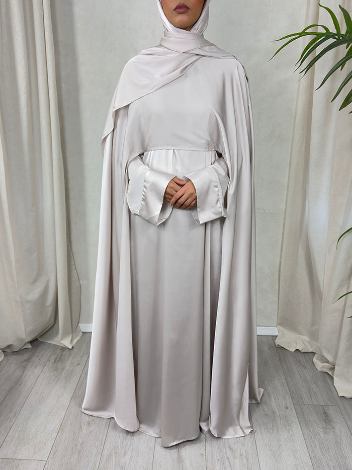 Side view of the nude cape abaya set showing the open satin cape and adjustable waist belt