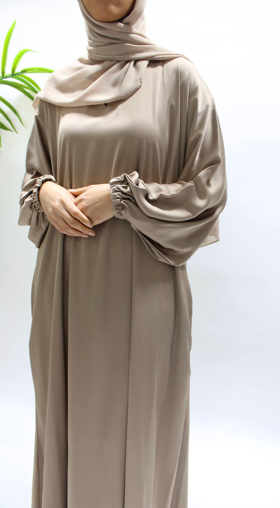 Woman wearing Amani's dark beige textured satin abaya with matching hijab