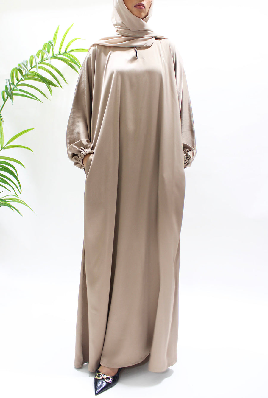 Full-length view of Amani's dark beige textured satin abaya