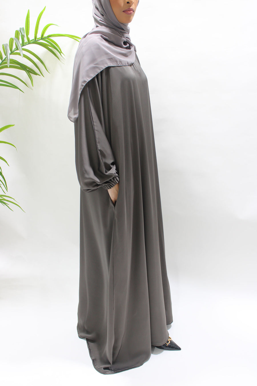 Woman wearing Amani's dark taupe textured satin abaya with matching hijab