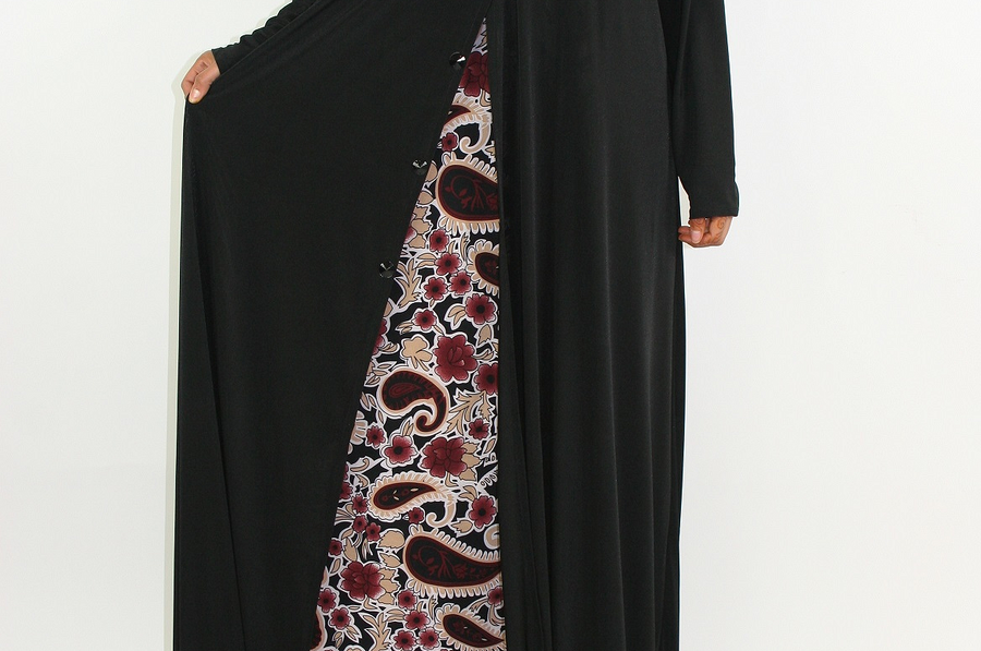 Azeeza abaya showing the burgundy paisley front panel and black satin flap