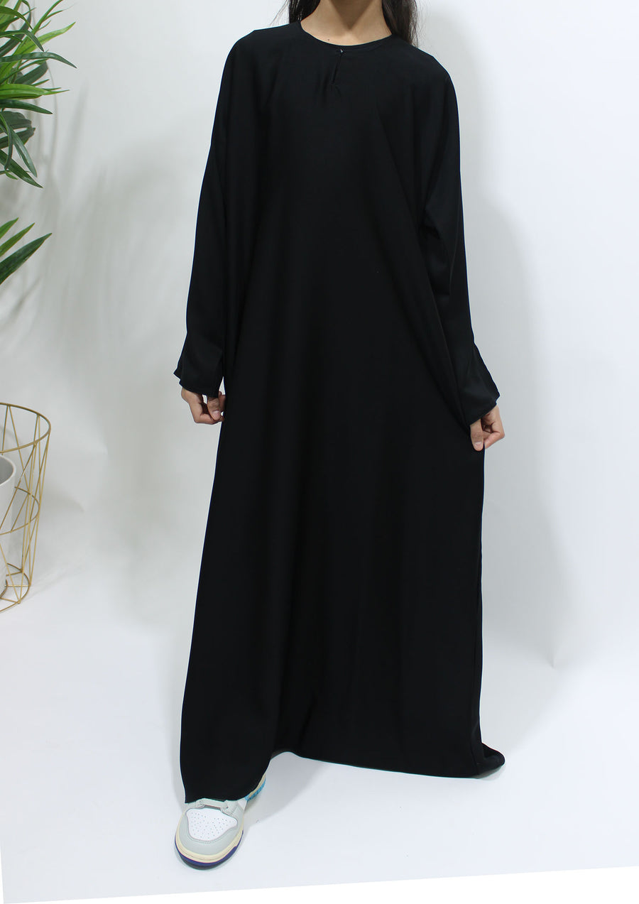 Full-length view of Amani's plain black girls' Neda abaya