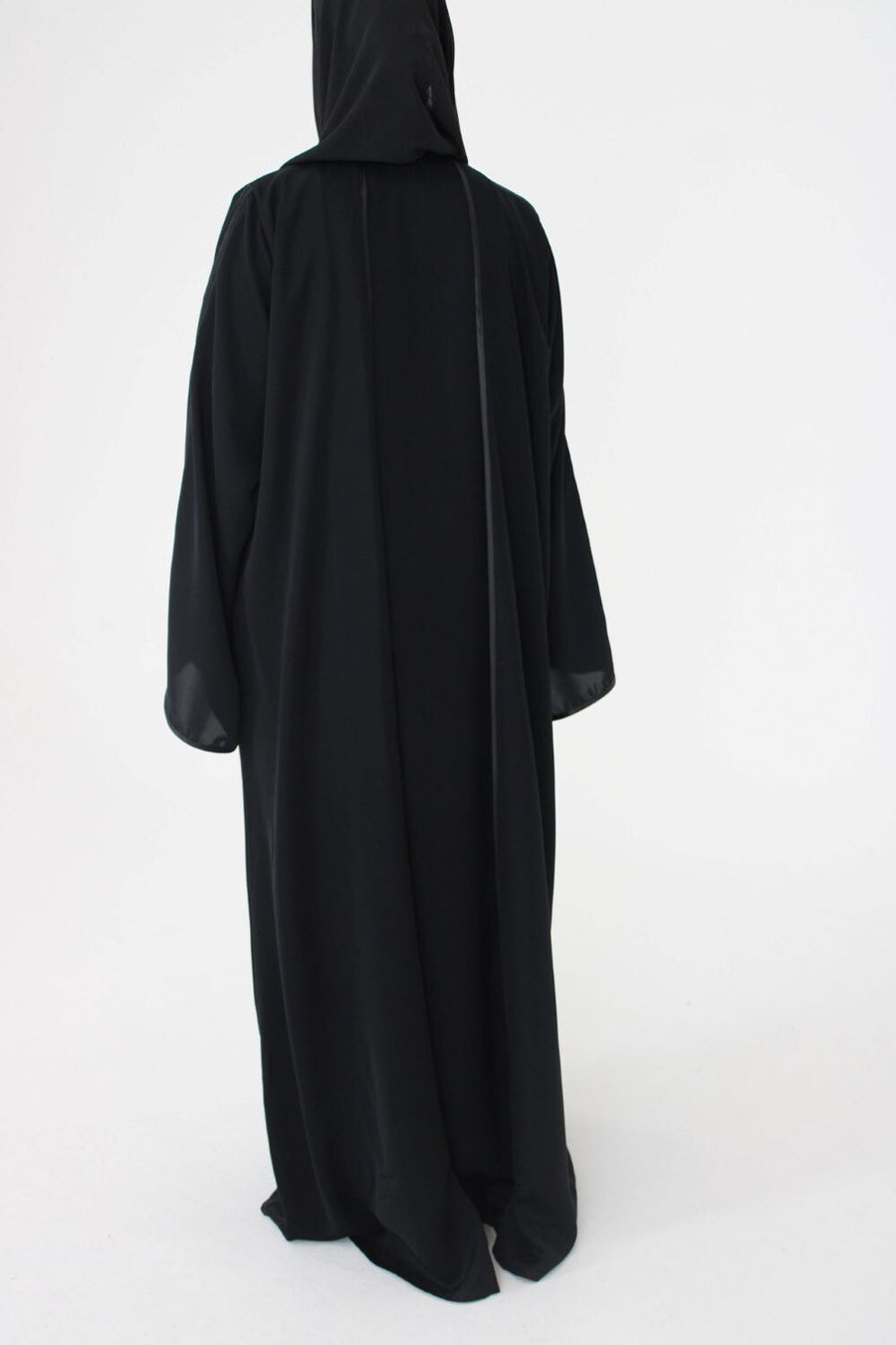 Full-length view of Amani's black open abaya with piping