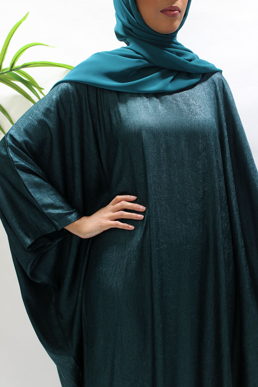 Side view of the teal farasha abaya showing its flowing drape