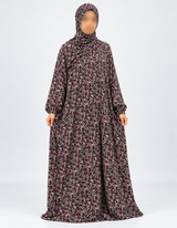 Amani's black and fuchsia floral one-piece prayer dress, full front view with sleeves hanging naturally down and attached hijab, no lace