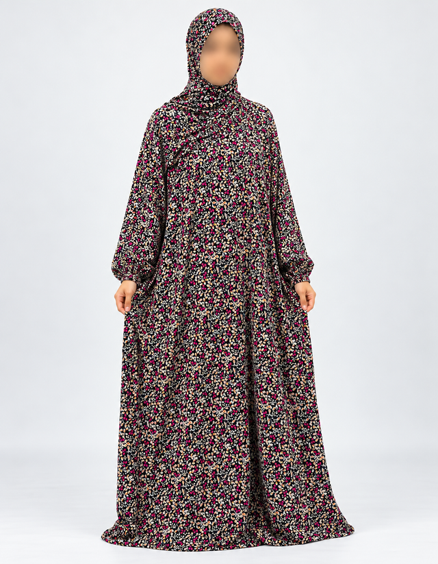 Amani's black and fuchsia floral one-piece prayer dress, full front view with sleeves hanging naturally down and attached hijab, no lace