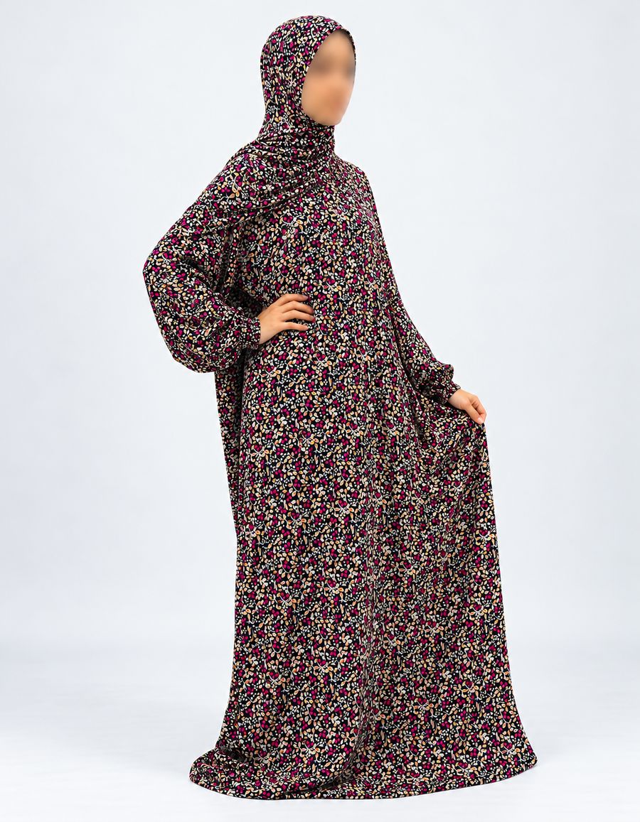 Black and fuchsia botanical prayer dress with attached hijab, angled view showing sleeves falling naturally and printed fabric