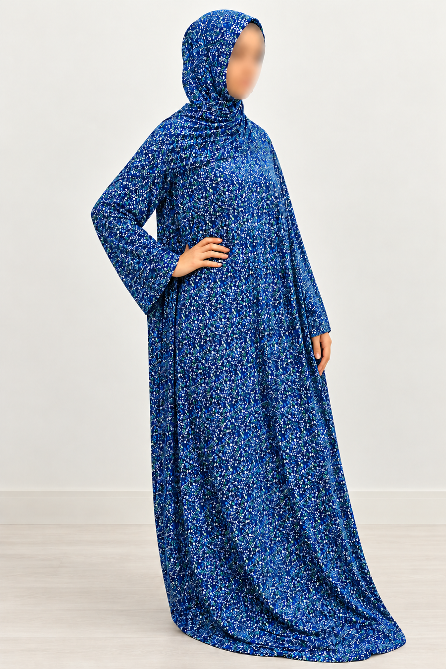 Three-quarter view of Amani's royal blue floral one-piece prayer dress, showing its straight-cut sleeves, attached hijab and no-lace finish