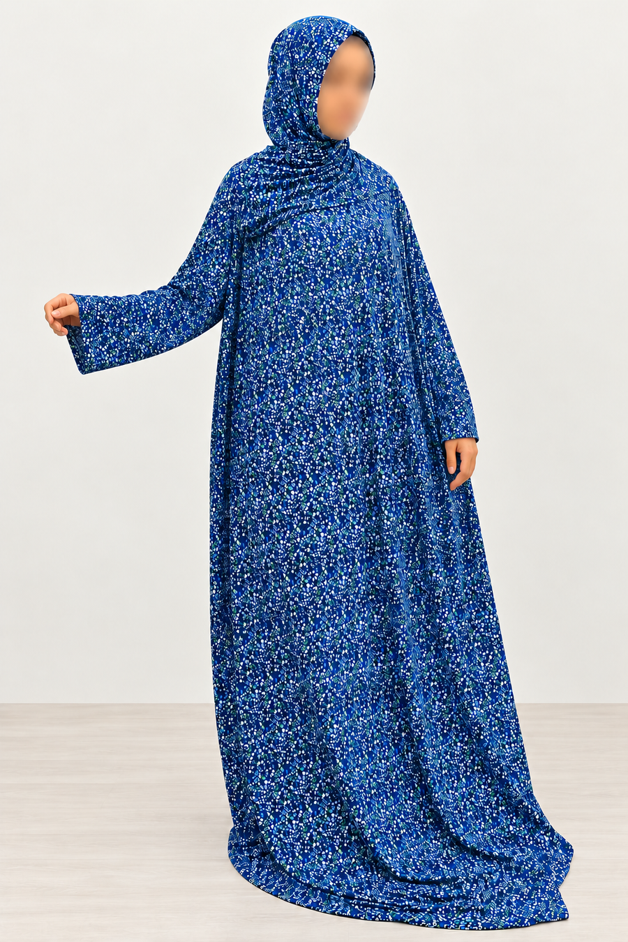 Amani's royal blue mini floral prayer dress with attached hijab, arm extended to show the straight-cut sleeve and small blue green floral print