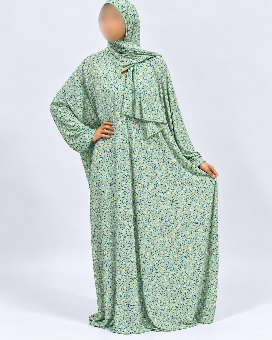 Soft green floral prayer dress with attached matching hijab, full-length three-quarter pose showing the flowing drape and no-lace finish