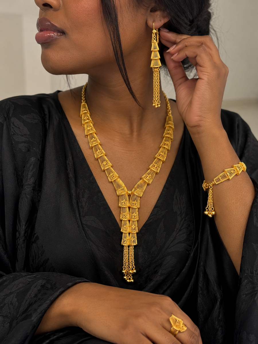 Model wearing gold-tone tiered tassel necklace earrings bracelet and ring