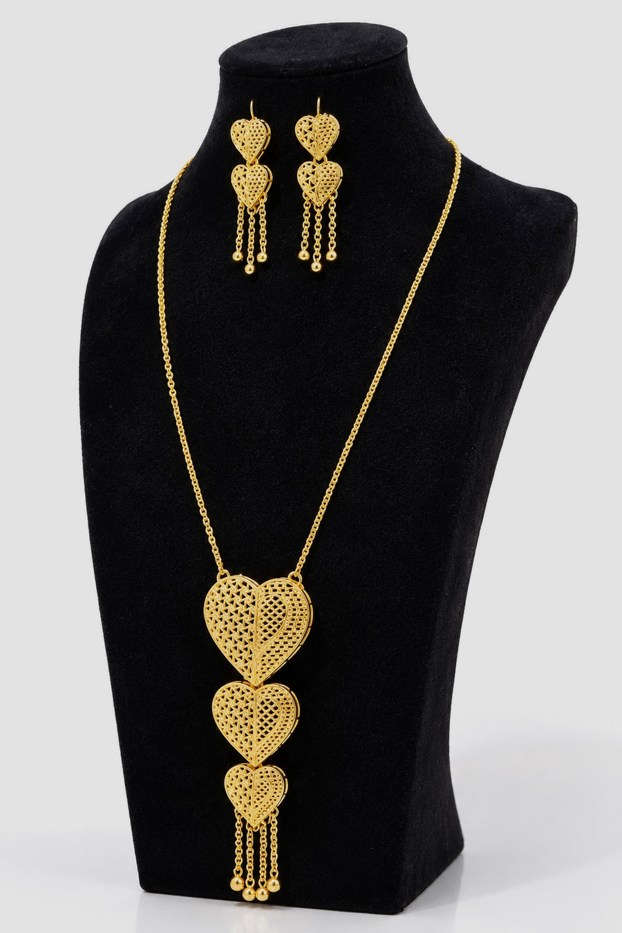 Angled view of gold-tone layered heart necklace with matching earrings