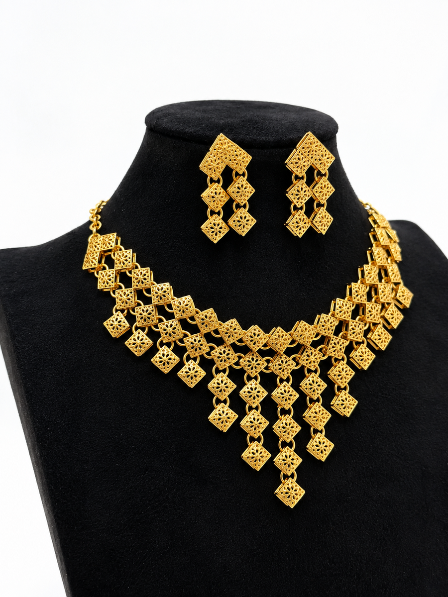 Angled view of gold-tone geometric filigree cascade necklace and earrings