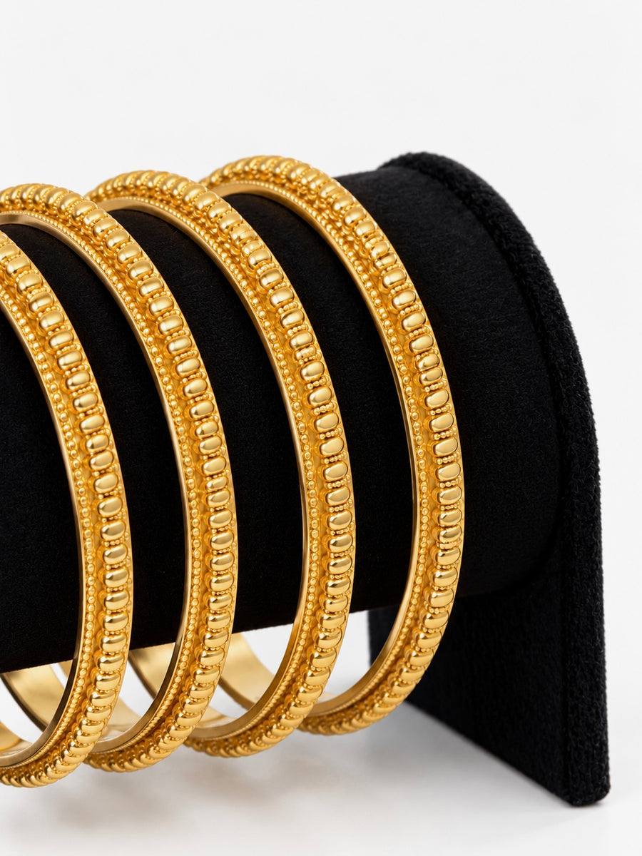 Close-up of gold beaded-link bangles on black jewellery stand