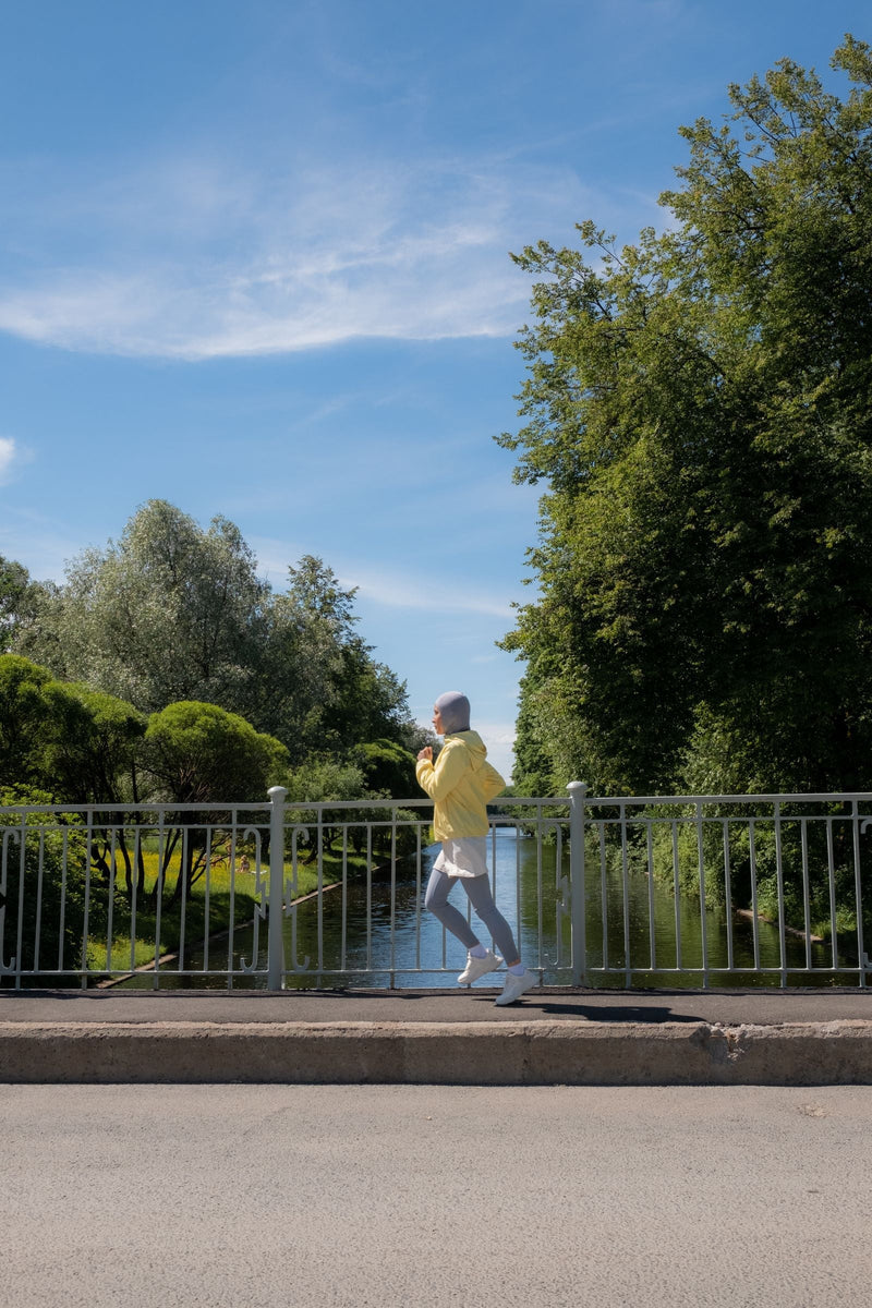Muslim woman wearing modest sportswear and a hijab while jogging outdoors, illustrating secure active clothing, movement and performance
