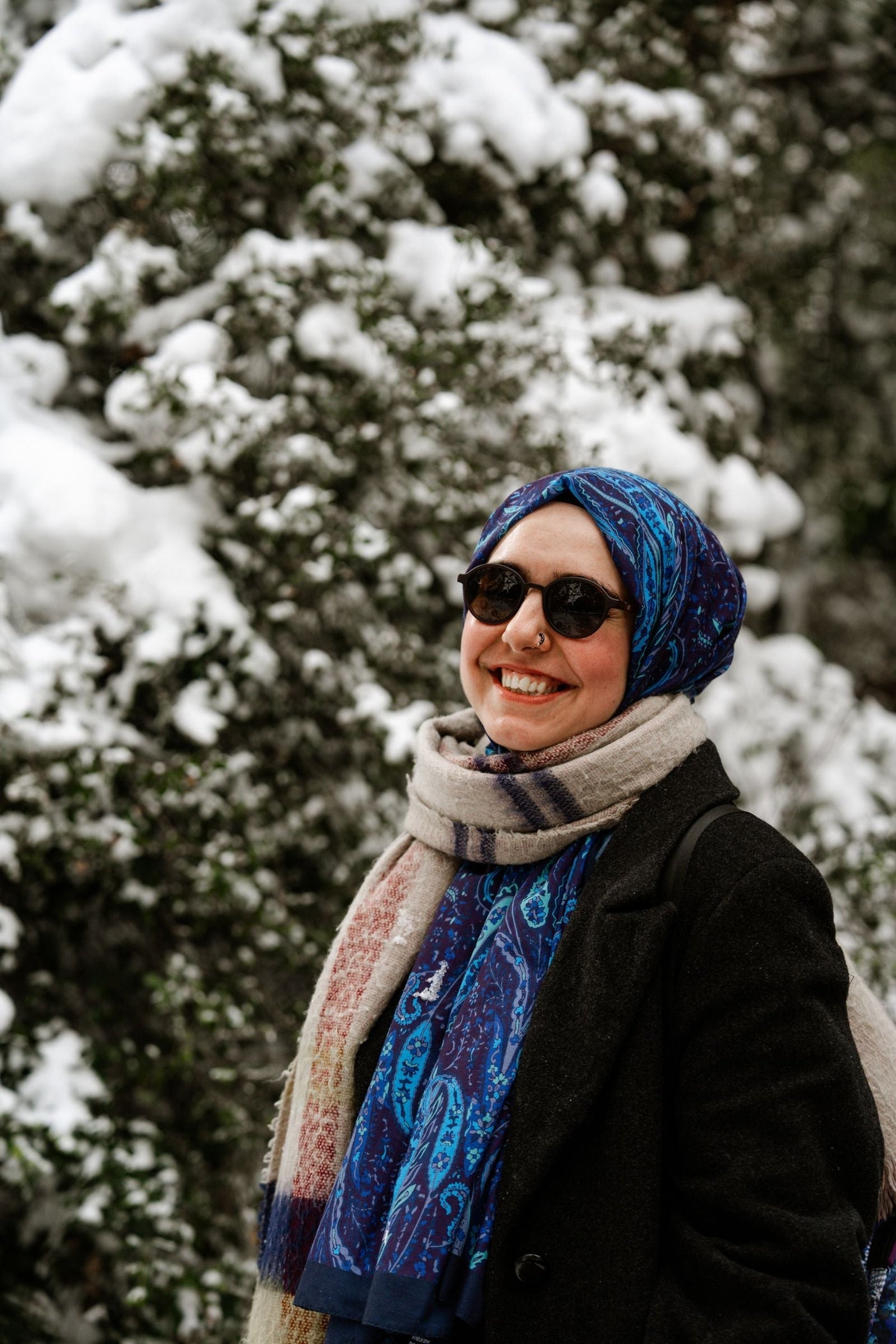 Muslim woman wearing a dark winter coat and blue hijab in snow, illustrating modest winter layers, warmth and practical style