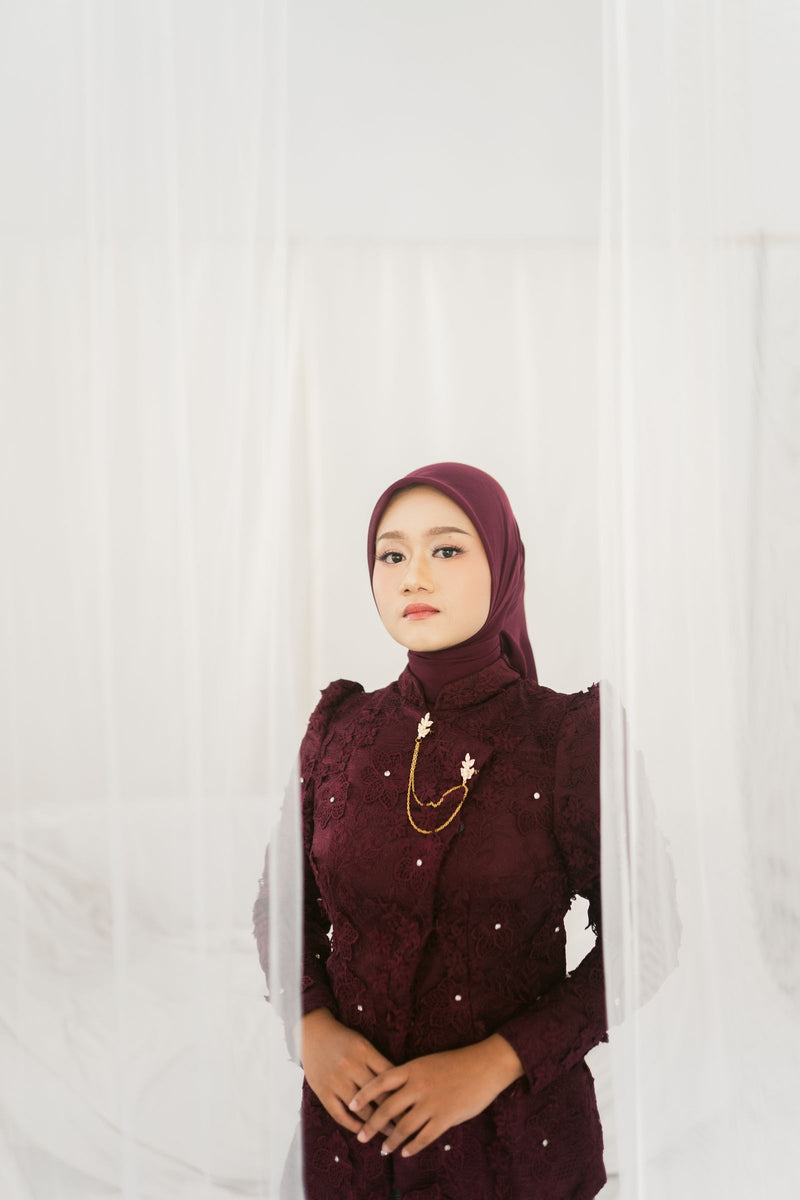 Muslim woman wearing an ornate maroon formal dress and matching hijab, illustrating modest maroon prom and evening styling