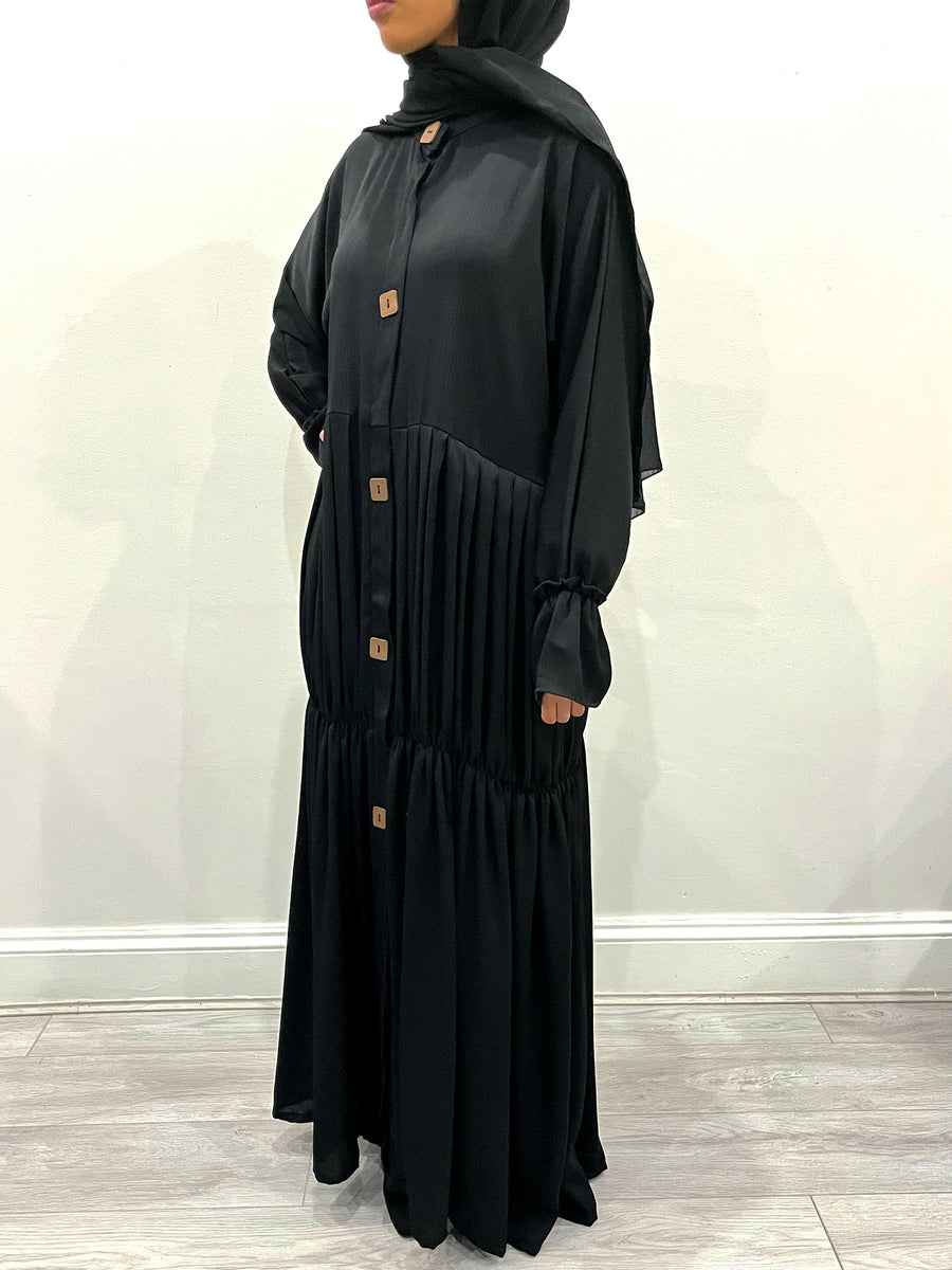 Black pleated abaya belted at the waist to show the pleated flare