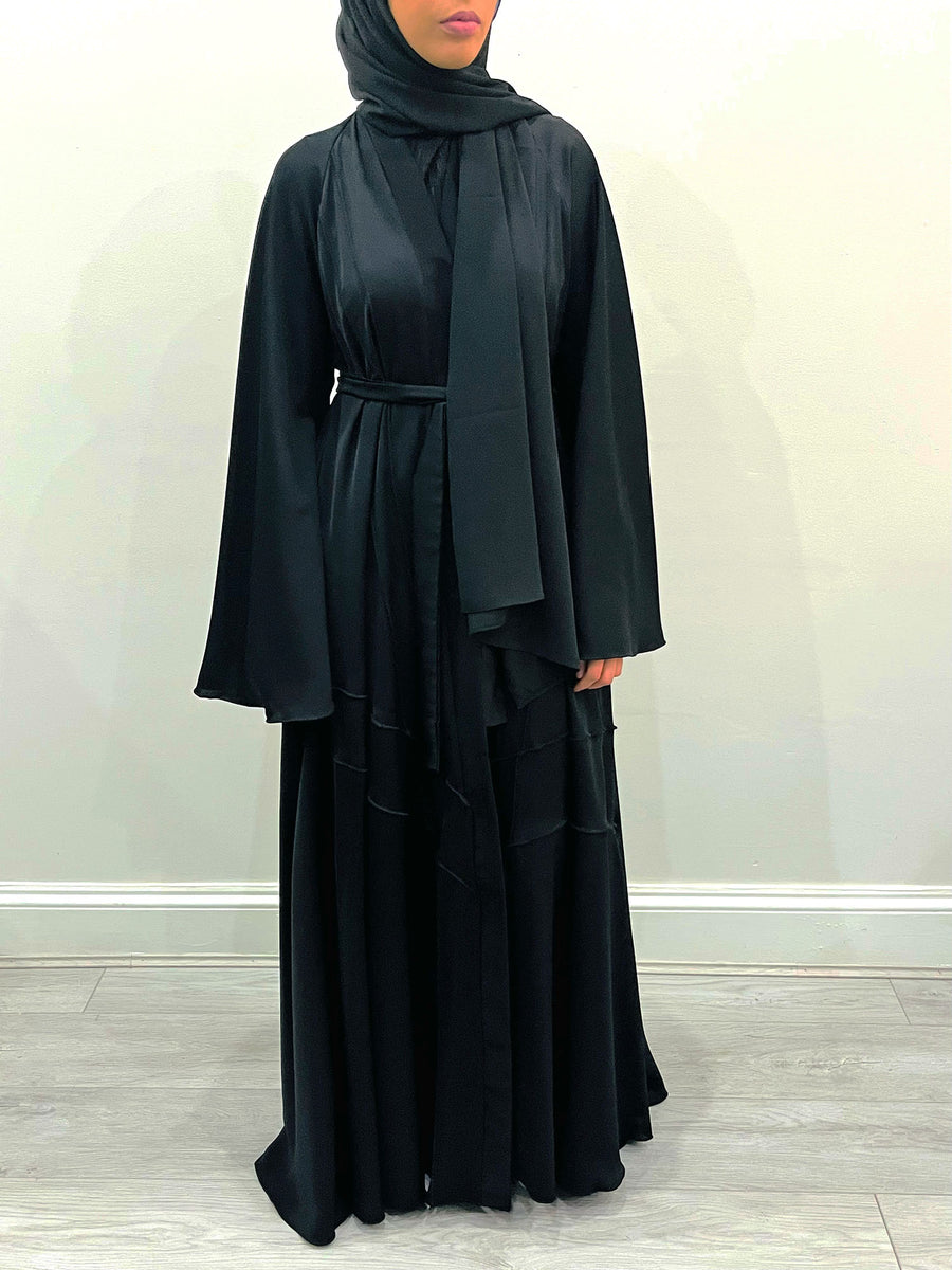 Black umbrella-cut abaya in motion showing the dramatic flare