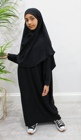 Girl wearing Amani's black abaya and khimar set, full-length front view