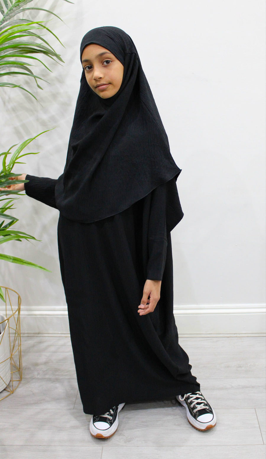Girl wearing Amani's black abaya and khimar set, full-length front view