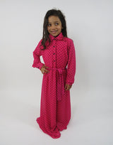 Girl wearing Amani's pink and black polka-dot long-sleeve kids maxi dress