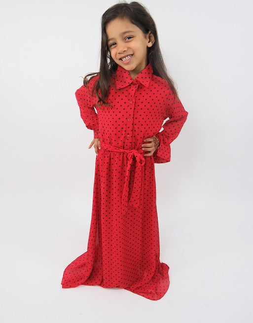 Girl wearing Amani's red and black polka-dot long-sleeve kids maxi dress