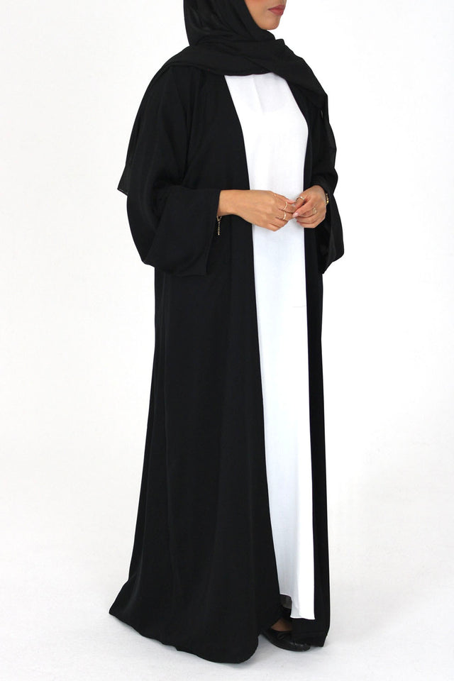 Black duster-style open abaya worn open over a maxi, front view