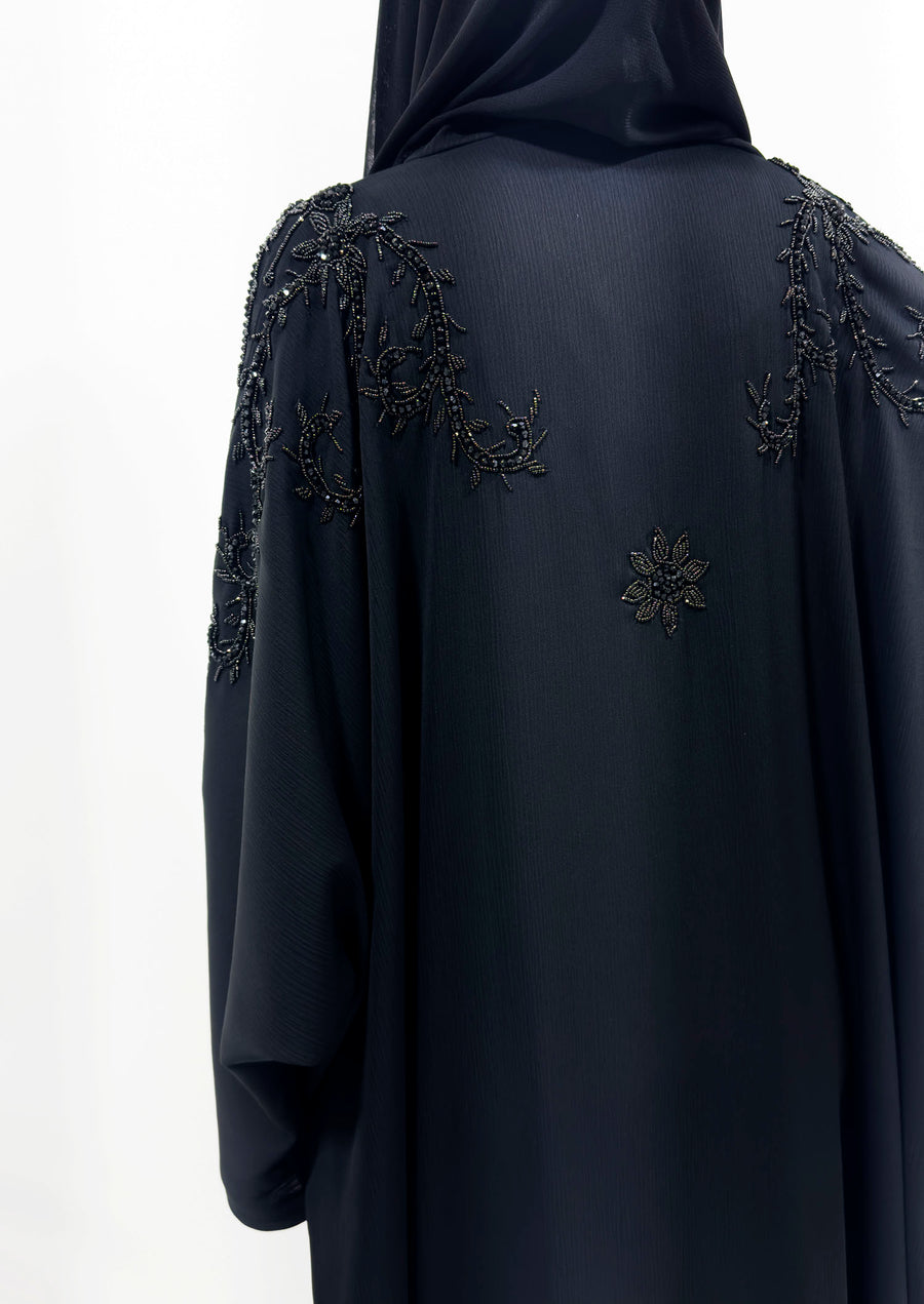 Side view of the black open batwing abaya showing its draped sleeves