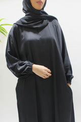Woman wearing Amani's black textured satin abaya with matching hijab