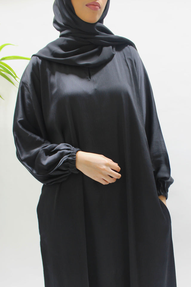 Woman wearing Amani's black textured satin abaya with matching hijab