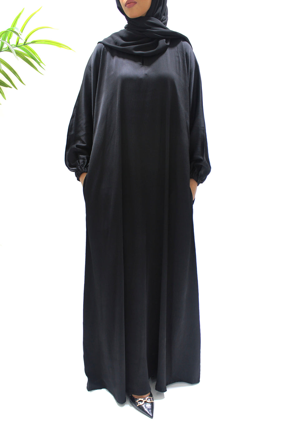 Full-length view of Amani's black textured satin abaya