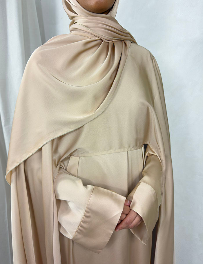 Close-up of the warm beige three-piece abaya set showing Armani satin fabric and matching scarf detail