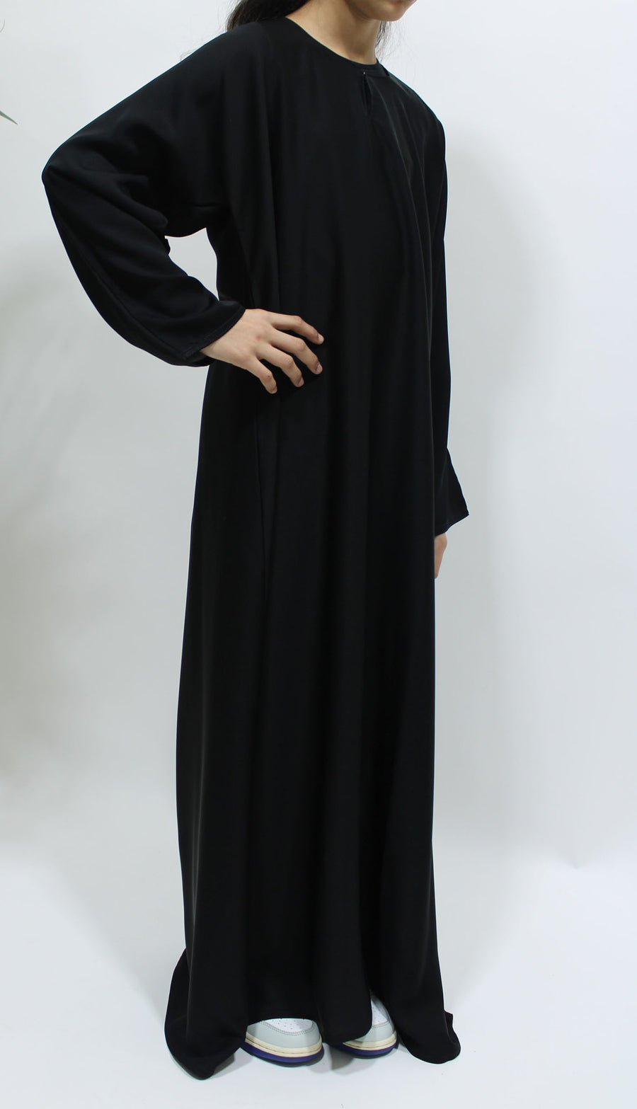 Plain black girls' closed abaya showing the flowing drape