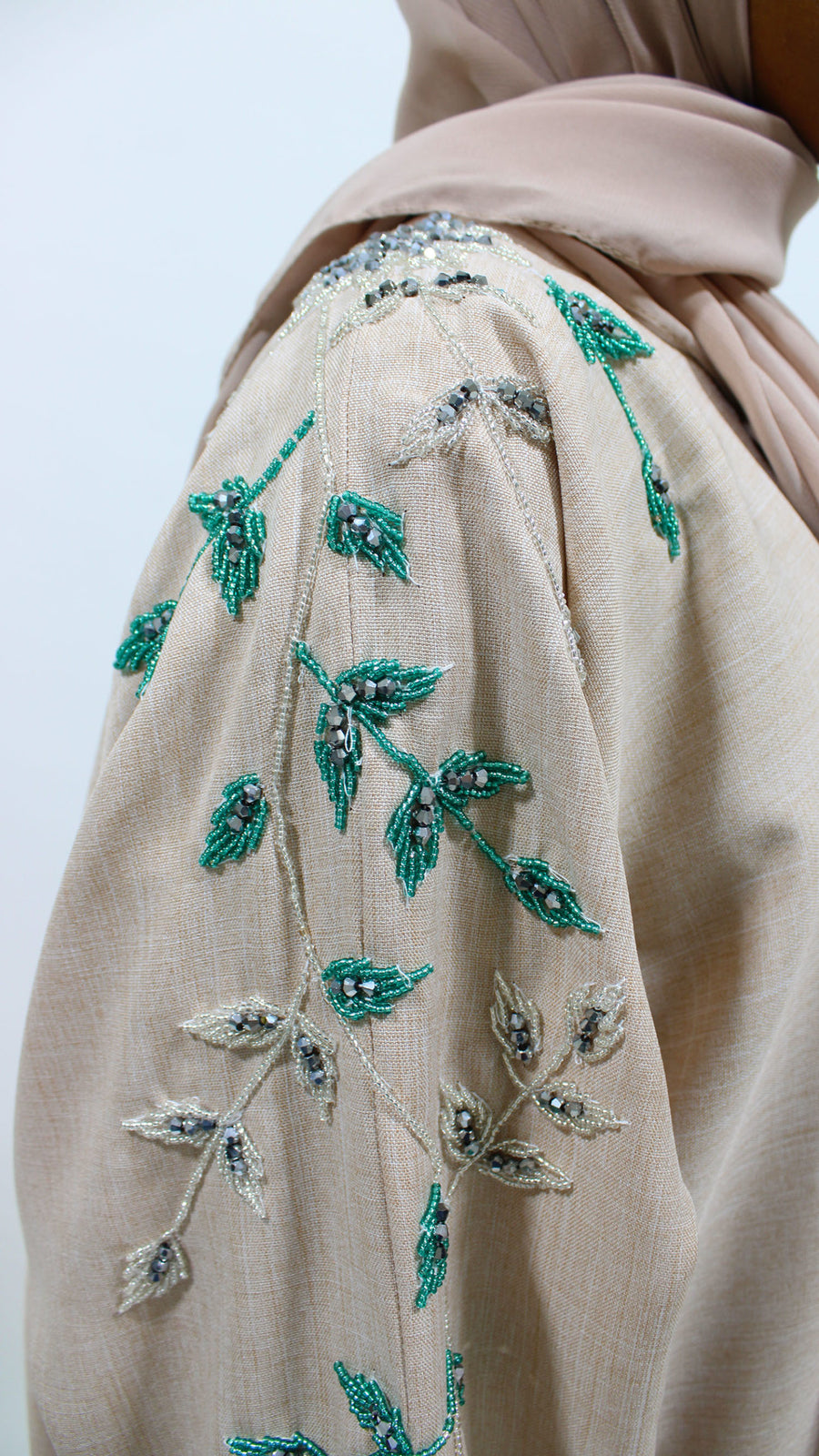 Close detail of the nude linen-blend fabric texture and sleeve stitching