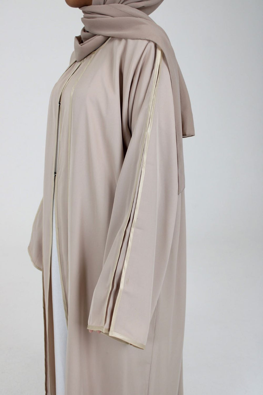 Full-length view of Amani's beige open abaya with piping
