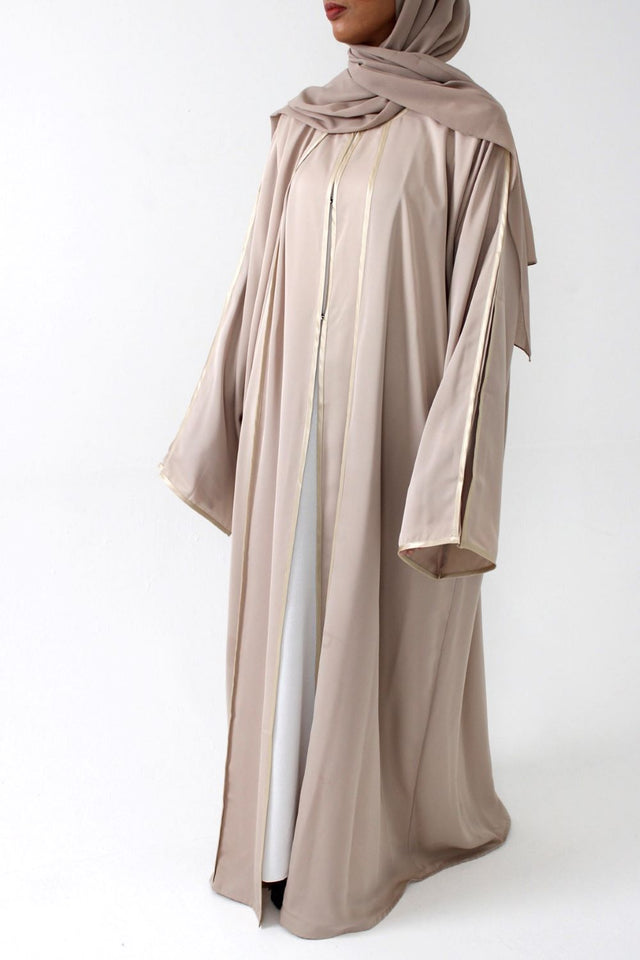 Woman wearing Amani's beige open abaya with satin piping and matching scarf