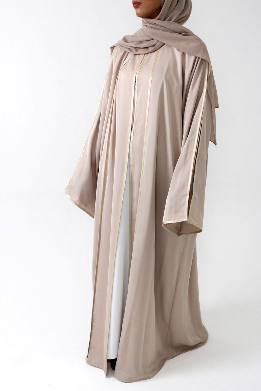 Woman wearing Amani's beige open abaya with satin piping and matching scarf