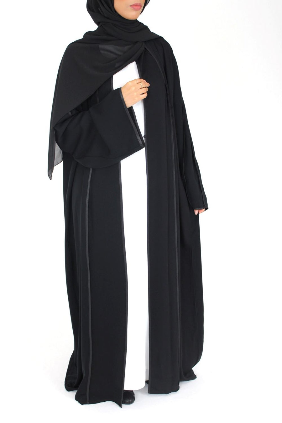 Woman wearing Amani's black open abaya with satin piping and matching scarf