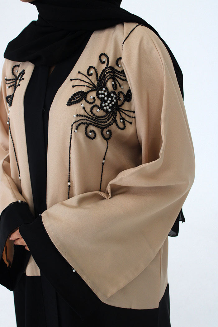 Detail of the hand embellishment on the cream and black abaya jacket