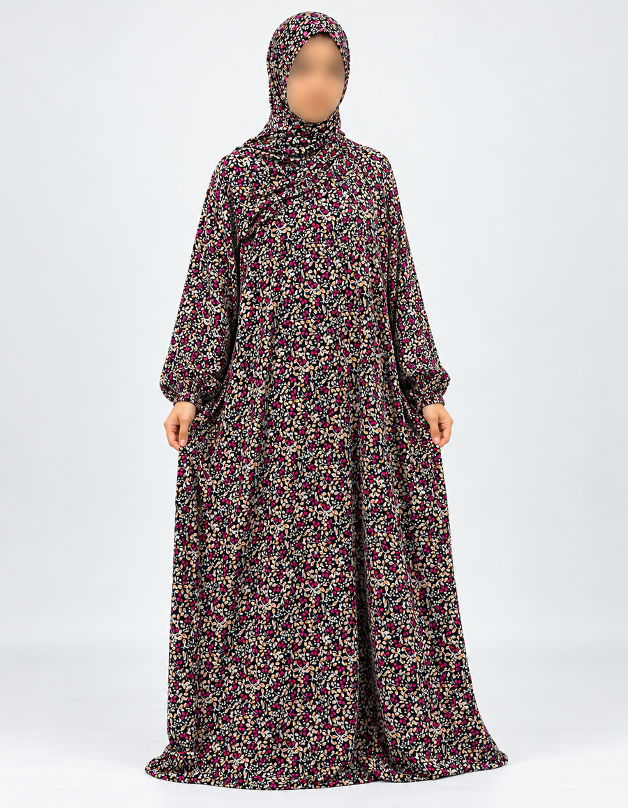 Amani's black and fuchsia floral one-piece prayer dress, full front view with sleeves hanging naturally down and attached hijab, no lace