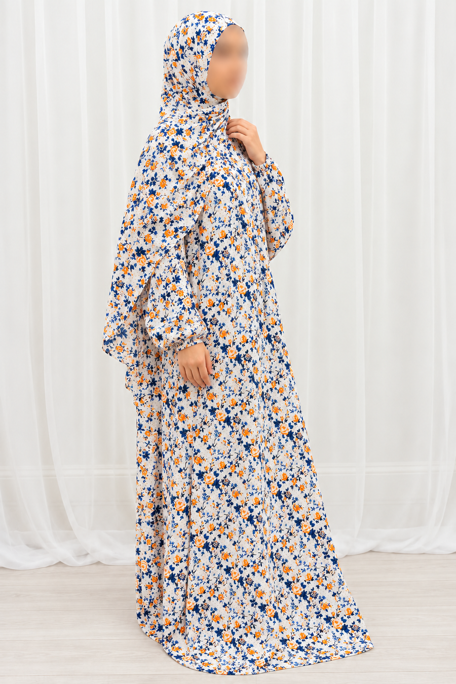 Amani's eggshell white floral one-piece prayer dress, three-quarter view showing the navy and orange print and full-length drape, no lace